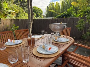 An outdoor dining table set with plates, glasses, and a large silver bucket. - Crab Shack Cottage: 4BR in Russell with Pool & Spa, 300m to Waterfront (Russell)
