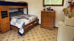 Ein Schlafzimmer mit Etagenbett, Kommode, Lampe und Fenster.