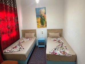 A room with two single beds, a nightstand, a red curtain, and a painting on the wall. - Hotel Youssef Sousse Medina (Sousse)