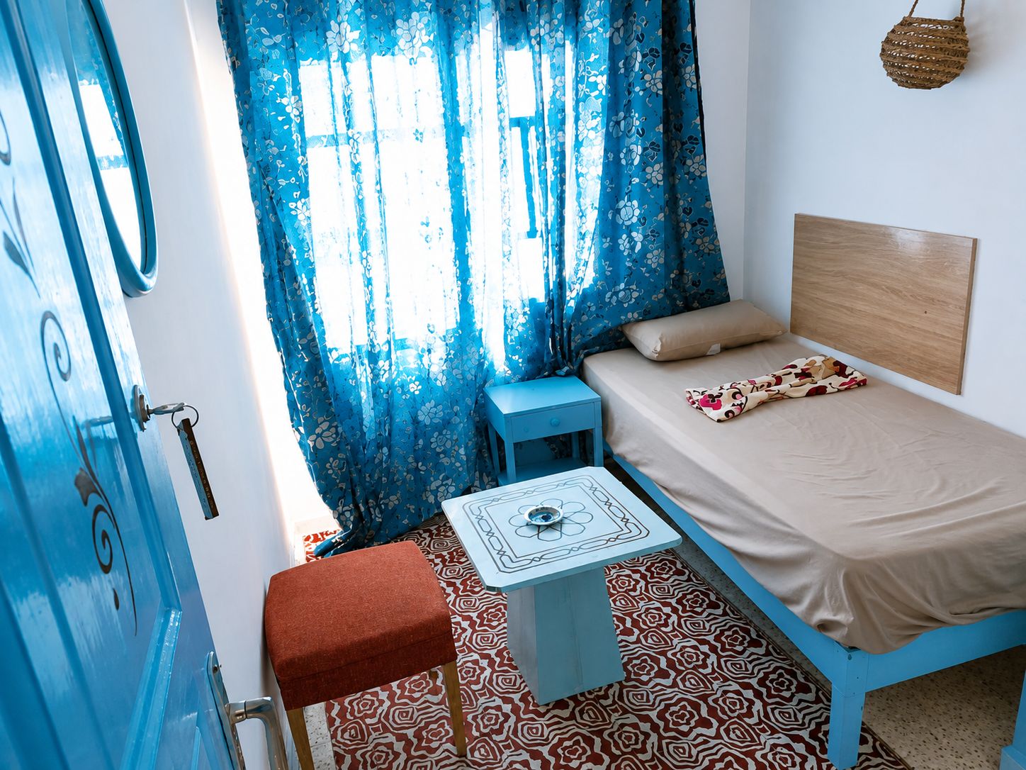 A room with a bed, a small table, a chair, and a door.
