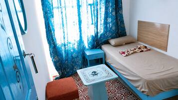 A room with a bed, a small table, a chair, and a door.