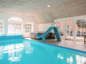 An indoor swimming pool with a blue slide, large windows, and a hot tub. - 4 Star Holiday Home in Ulfborg (Ulfborg)