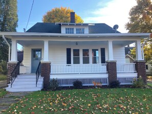 A two-story house with a front porch, a chimney, and a satellite dish. - Cozy 2-bedroom bungalow in gorgeous Jamestown with AC (Jamestown)