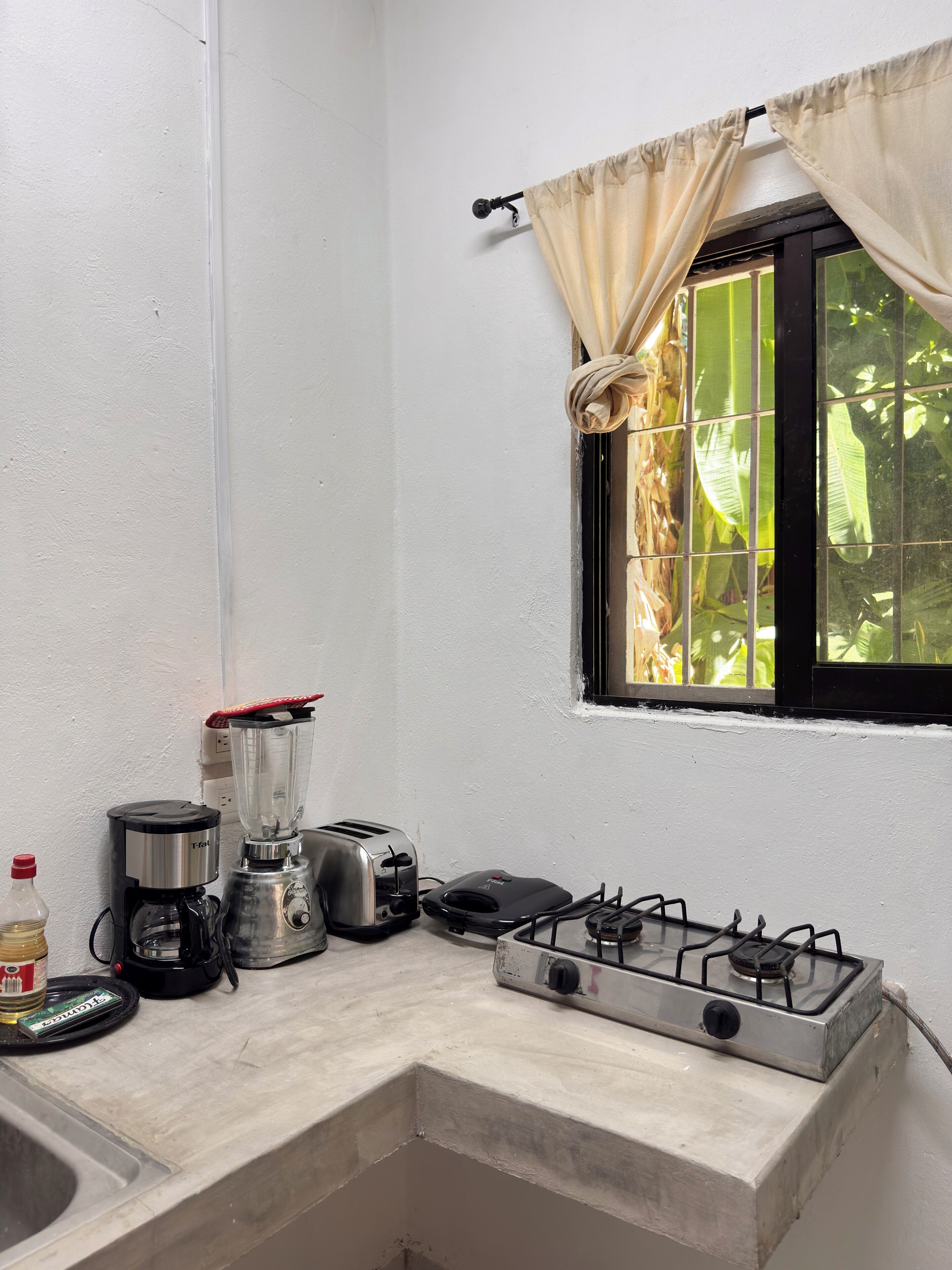 Une cuisine équipée d’une cuisinière à gaz, d’un grille-pain, d’un mixeur et d’une machine à café.