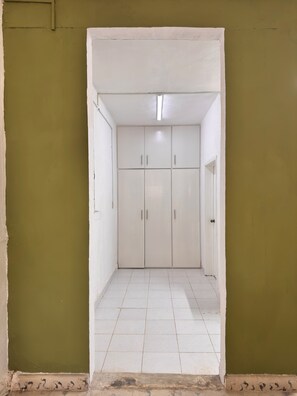 A corridor with a white tiled floor leading to a set of white cabinets with silver handles.