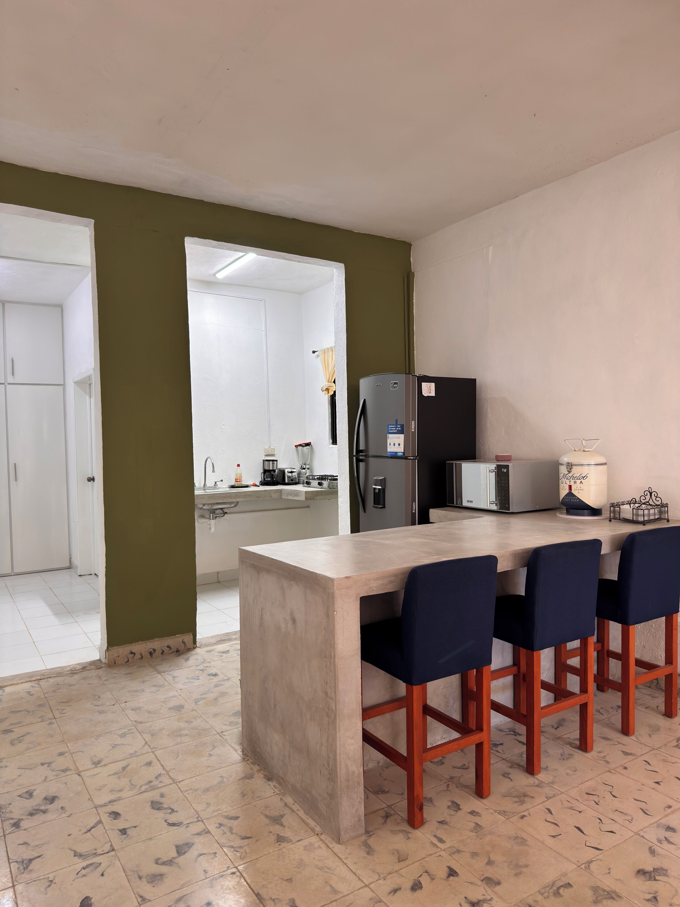 Une cuisine moderne dotée d’un îlot central, de tabourets de bar et d’un réfrigérateur.