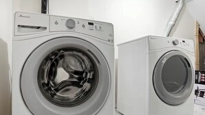 Vue de face d’un lave-linge Amana à chargement frontal, de couleur blanche, doté d’un panneau de commande et d’une porte en acier inoxydable.