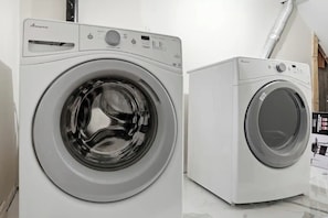 A front view of a white Amana front-loading washing machine with a control panel and a stainless steel door.