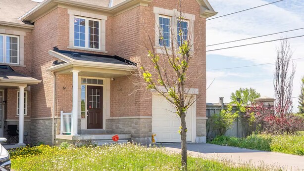 Une maison à deux étages avec une façade en briques, un porche à l’avant et un garage.