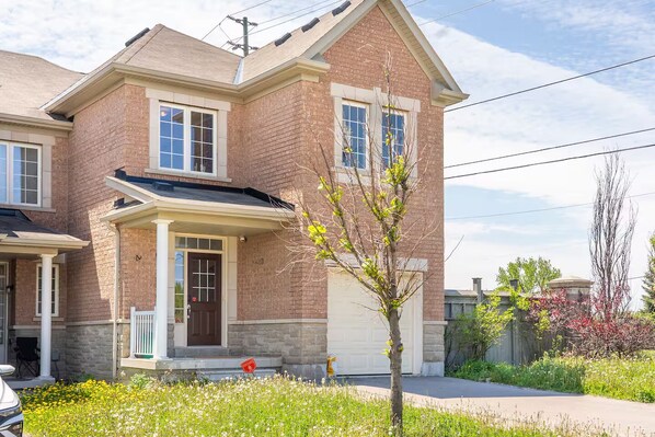 A two-story house with a brick facade, a front porch, and a garage.
