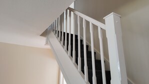 Una escalera blanca con techo texturizado y un rellano alfombrado.