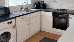 Cocina compacta equipada con lavadora, lavavajillas, microondas, cocina y fregadero.