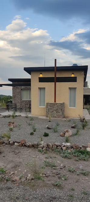 A modern house with a stone facade, two windows, and a gravel driveway.