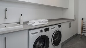 A modern laundry room with a Bosch washing machine, a sink, and neatly folded towels on the counter.