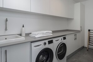 A modern laundry room with a Bosch washing machine, a sink, and neatly folded towels on the counter.