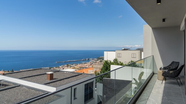 A balcony with a clear view of the sea and a coastal town.
