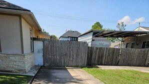 Ein Wohngrundstück mit Auffahrt, Holzzaun, Betonweg und Rasenfläche.