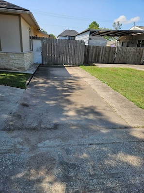 Ein Wohngrundstück mit Auffahrt, Holzzaun, Betonweg und Rasenfläche.