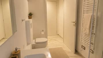 Un bagno moderno con una vasca da bagno ampia, un water e una zona doccia.