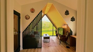 Et moderne interiør med en trappe, der fører til en balkon, et skrivebord med stol og dekorativ vægkunst.