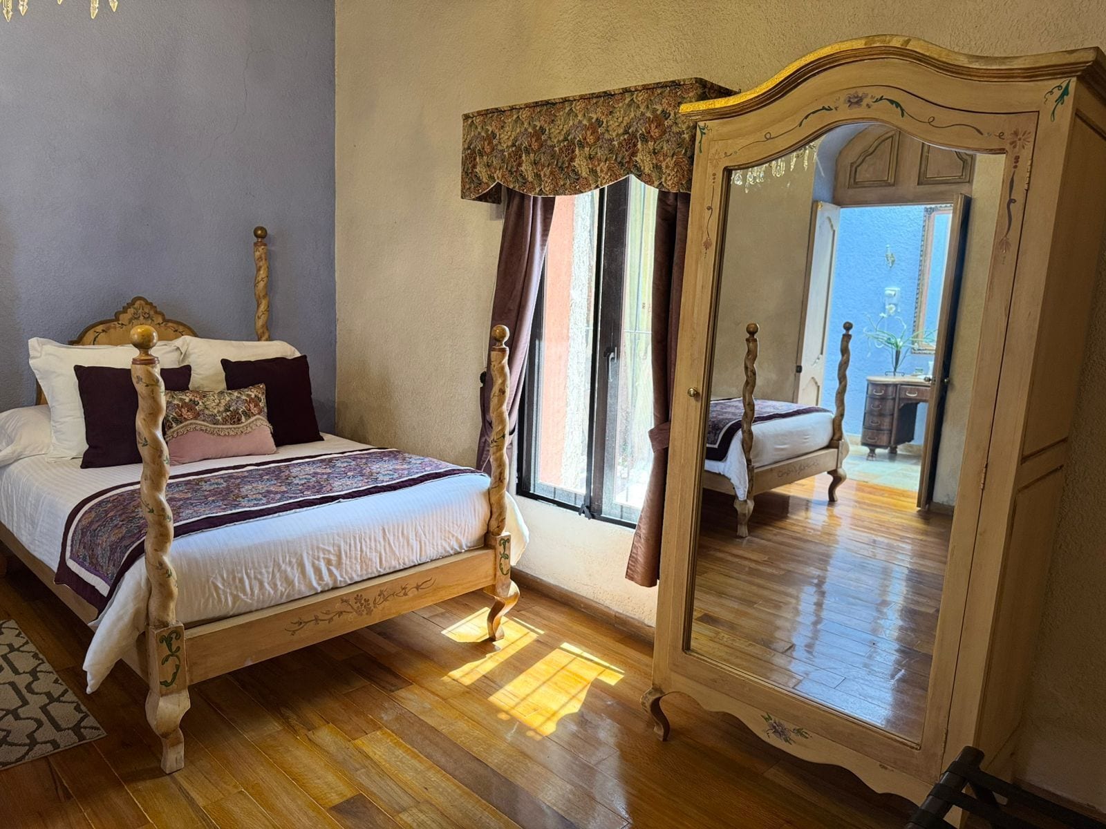 Una cama con dosel tradicional, un espejo grande y vistas a un balcón.