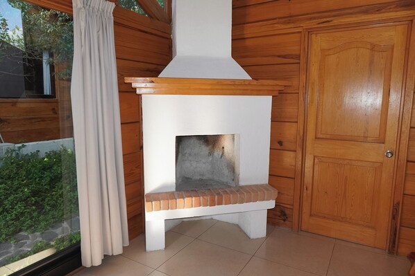 Um quarto com painéis de madeira, lareira, uma porta e uma janela com cortinas.