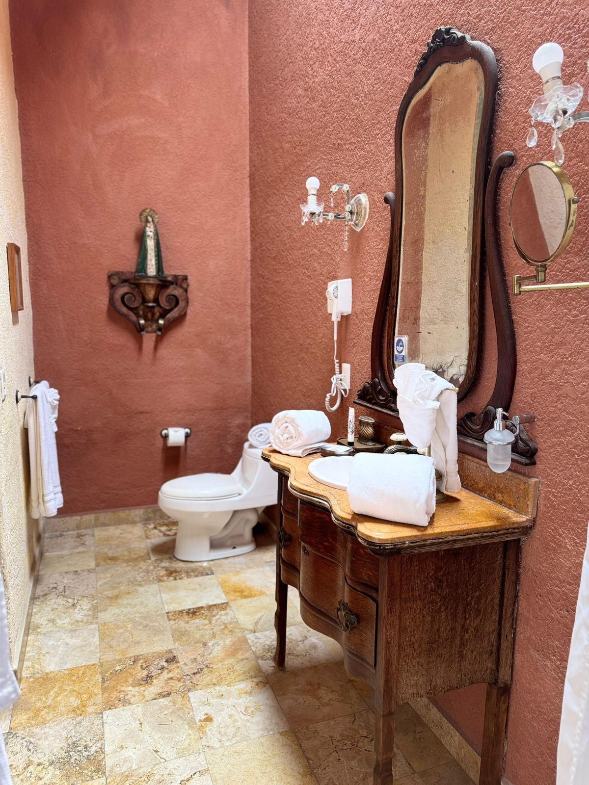 Un baño con tocador de madera, espejo, inodoro y perchero para toallas.