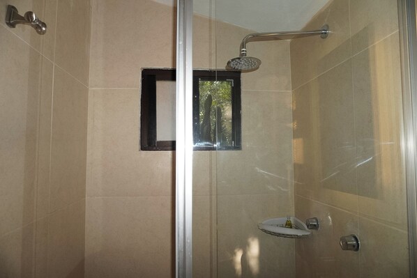 A glass-enclosed shower with a handheld showerhead, a small window, and a built-in sink with a soap dispenser. - CABAÑAS BERNAL & HOTEL & SUITES (Ezequiel Montes)