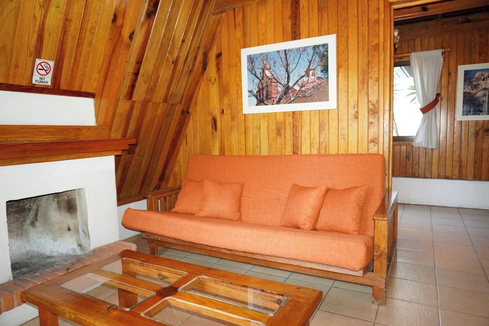 A wooden interior with a sofa, a fireplace, and a framed picture on the wall.
