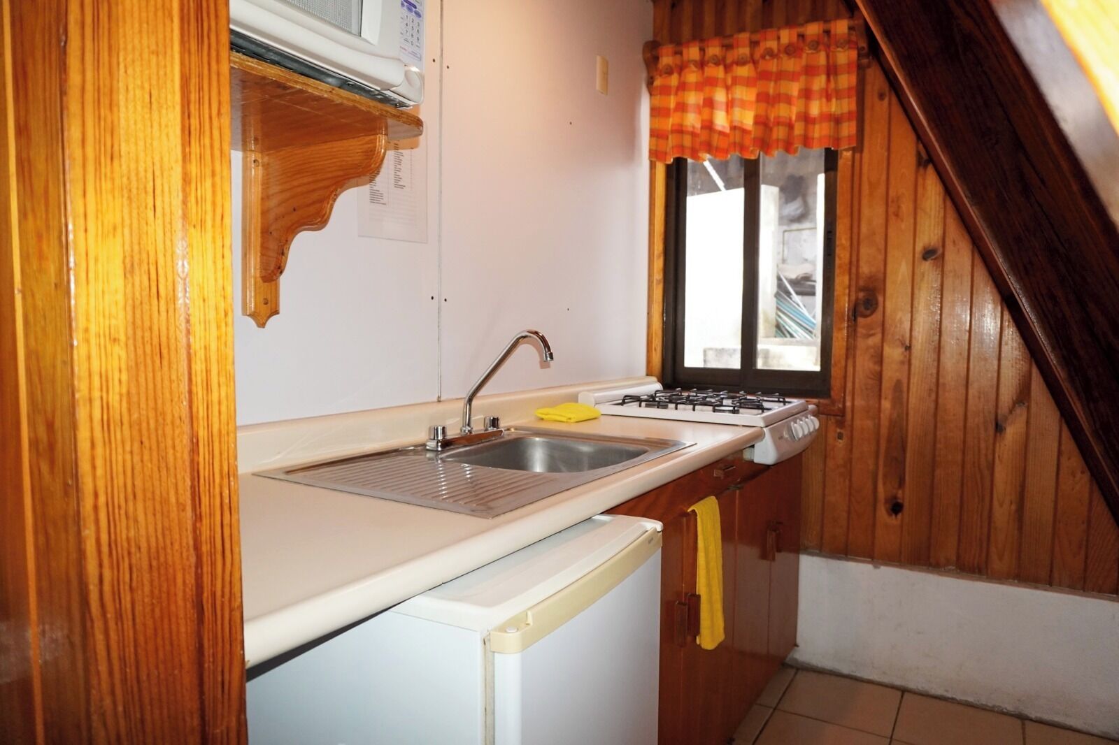 Una cocina compacta con fregadero, estufa y armarios de madera.