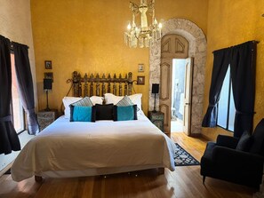 A hotel room with a large bed, a chandelier, a wooden headboard, and a view of the outside. - CABAÑAS BERNAL & HOTEL & SUITES (Ezequiel Montes)