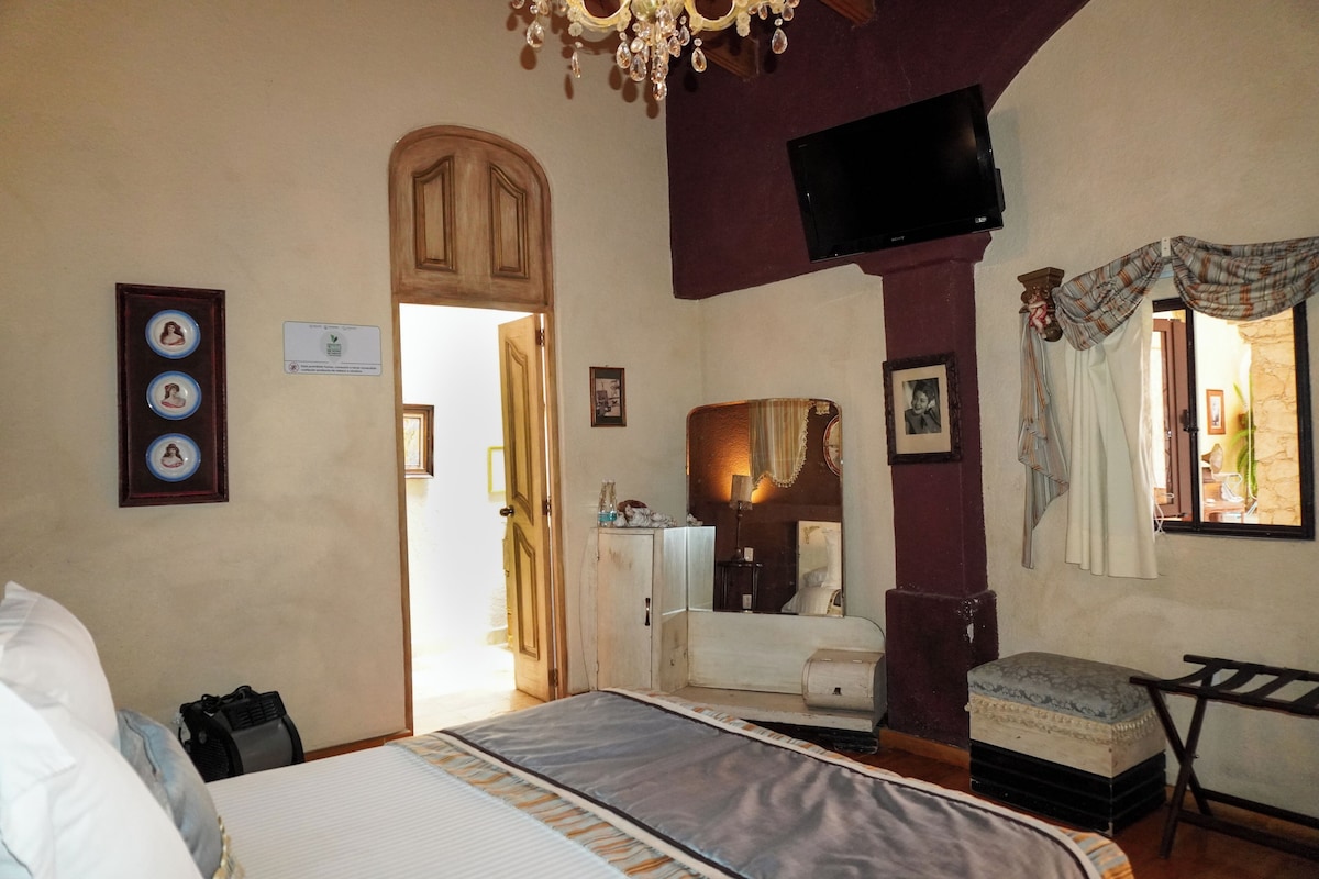 Un dormitorio con cama, cómoda, espejo y televisor.