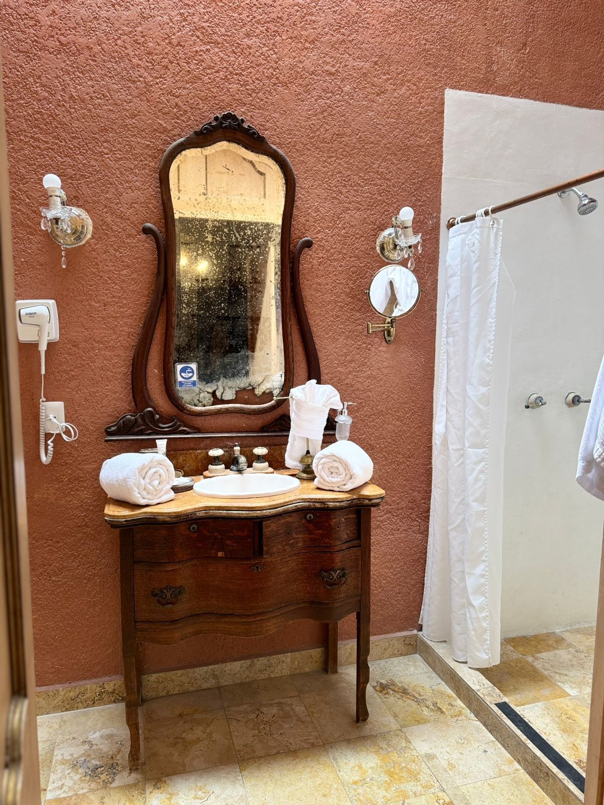 Un baño con tocador de madera, un espejo grande, un lavamanos y una cortina de ducha.