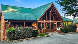 A lodge with a green metal roof, wooden exterior, and a welcoming entrance. - Southern Style - Hot Tub with TV, Game Room, Kids' Playhouse + Cornhole (Sevierville)
