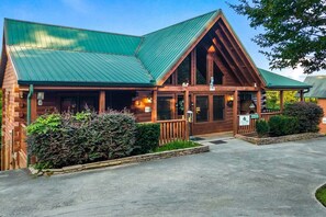 A lodge with a green metal roof, wooden exterior, and a welcoming entrance. - Southern Style - Hot Tub with TV, Game Room, Kids' Playhouse + Cornhole (Sevierville)
