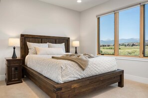 A bedroom with a large bed, two bedside tables, a window with a mountain view, and a wooden headboard. - Coyote Creek 1602 I Private Hot Tub I Great Views I Bunk Room I Discounted Attractions (Tabernash)