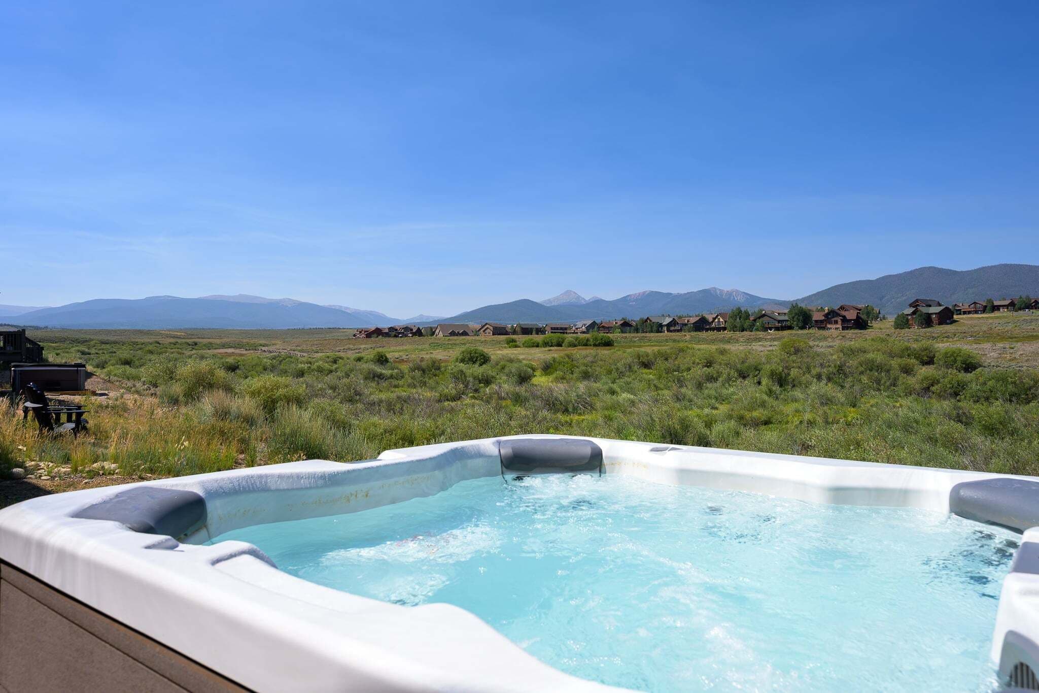 Ein Whirlpool auf einer Terrasse mit einer Berglandschaft im Hintergrund.