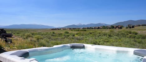 Ein Whirlpool auf einer Terrasse mit einer Berglandschaft im Hintergrund.