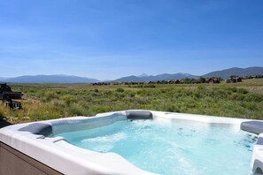 Ein Whirlpool auf einer Terrasse mit einer Berglandschaft im Hintergrund.