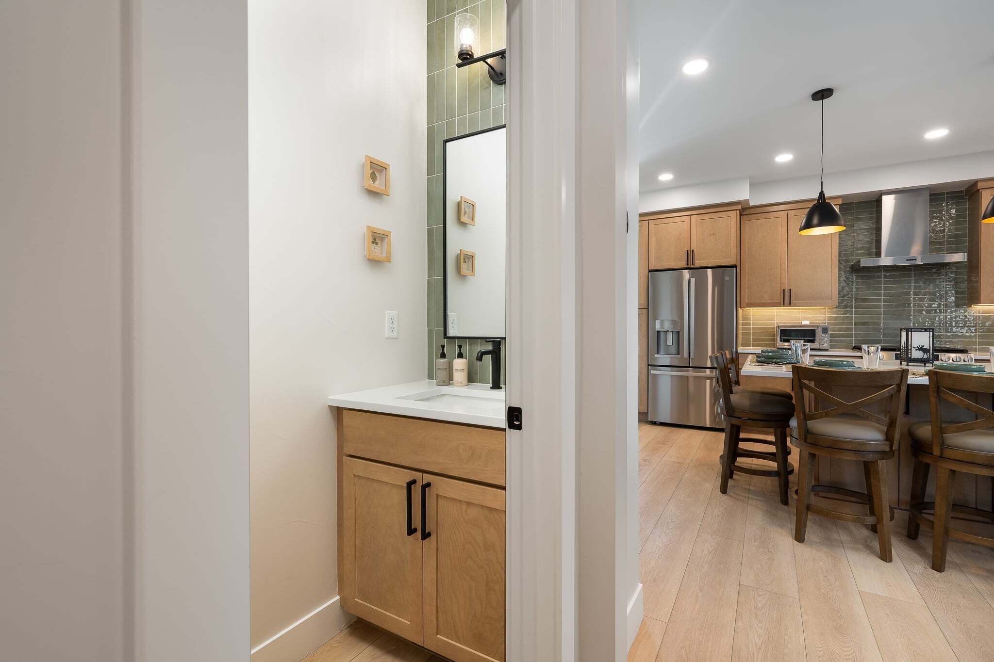 A modern kitchen with wooden cabinets, stainless steel appliances, and a dining area with wooden chairs.