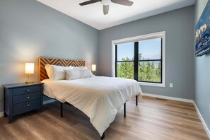 A bedroom with a bed, nightstands, a ceiling fan, and a large window with a view. - Milky Way Mountain Chalet I Private Hot Tub I Great Views I Bunk Room I Discounted Attractions (Fraser)