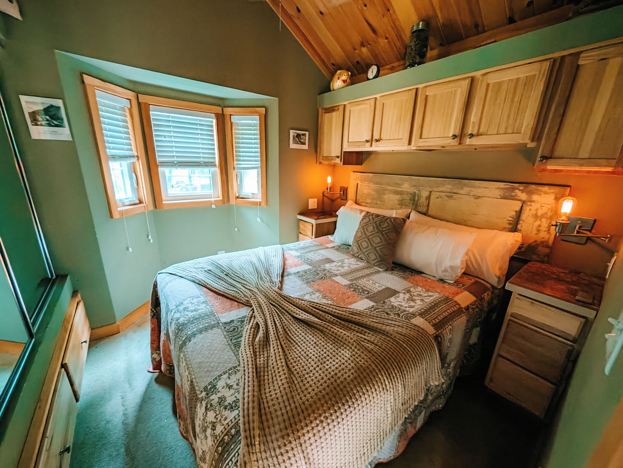 A bedroom with a bed, a nightstand, a dresser, and a window with blinds.
