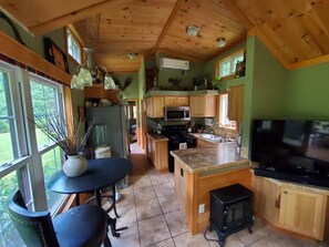A kitchen with wooden cabinets, a refrigerator, a microwave, a stove, and a television.