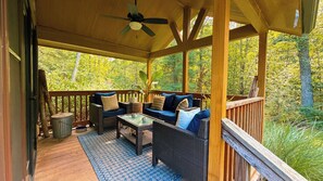 A covered outdoor seating area with wicker furniture and a ceiling fan.