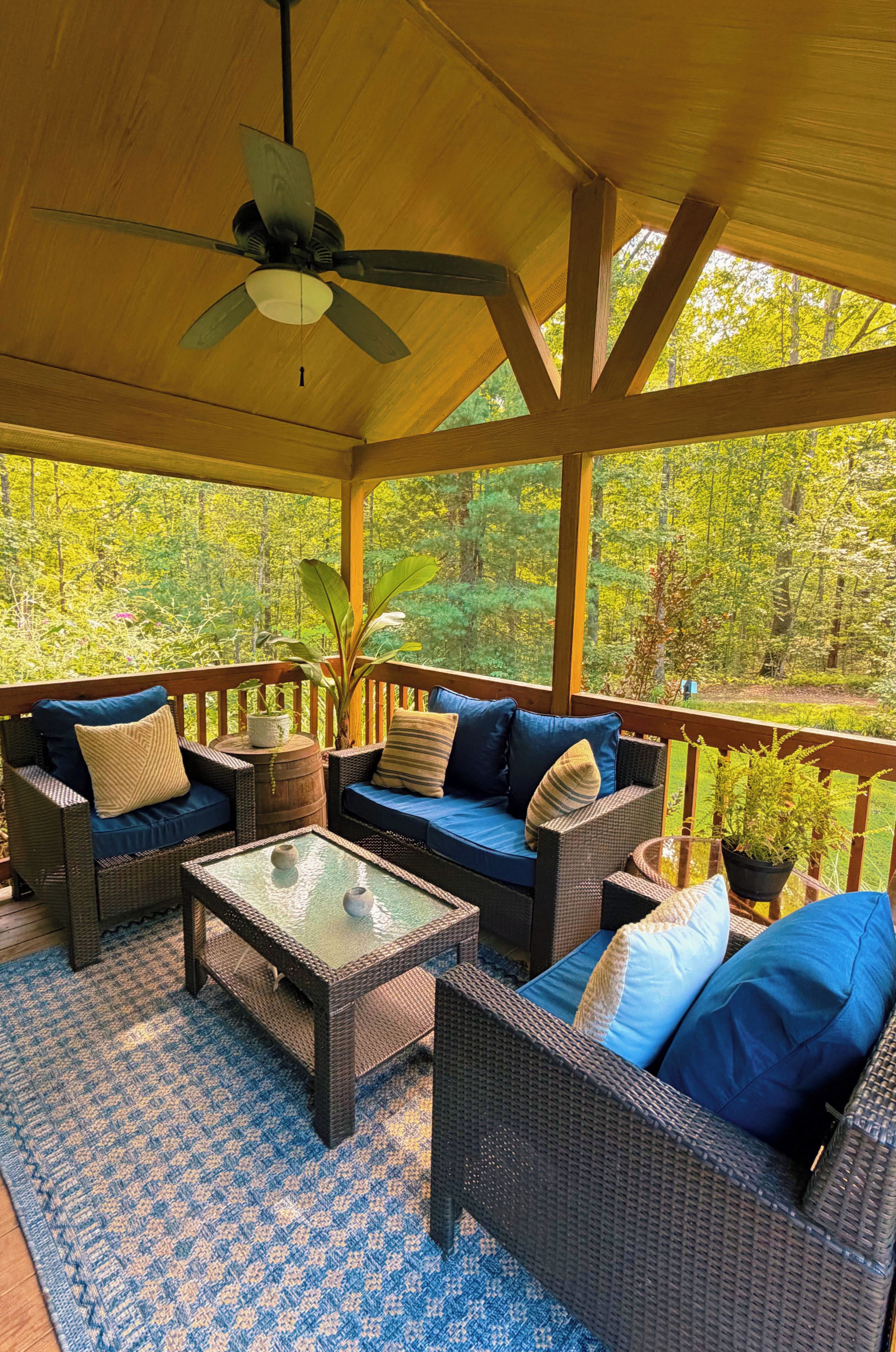A covered outdoor seating area with wicker furniture and a ceiling fan.