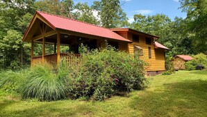 Eine Holzhütte mit rotem Dach, umgeben von üppigem Grün und Bäumen.