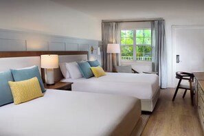 Habitación de hotel con dos camas, un escritorio y una ventana con cortinas.