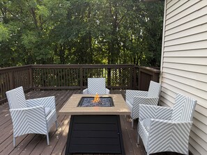 Una terraza con una mesa para fogata y sillas de mimbre.