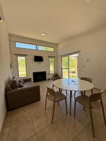 Uma sala de estar espaçosa com uma mesa redonda e cadeiras, um sofá e uma lareira.