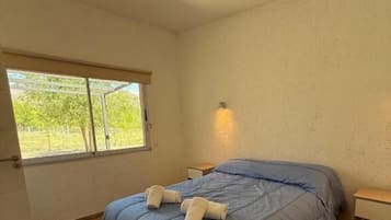 A bedroom with a bed, a window, and a nightstand.